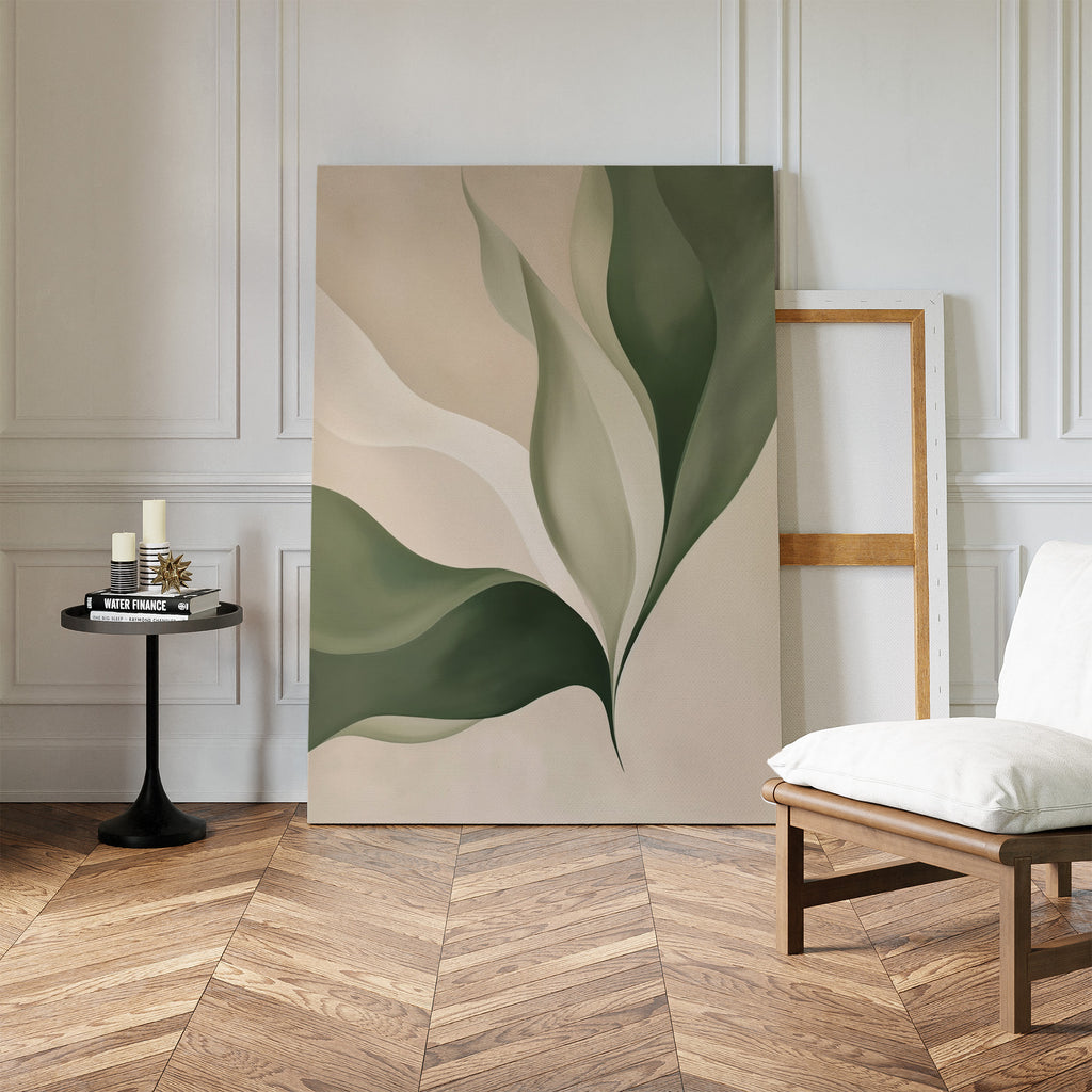 Verdant Grace, a large abstract minimalist wall art featuring green and beige leaf shapes, leans against a white paneled wall, enhancing the stylish living room decor alongside an empty frame, white chair, and black table with candles on herringbone floors.