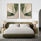 A modern bedroom features an olive green bed, white bedding, two round nightstands with beige lamps, and the Verdant Grace Set of 2—minimalist wall art with abstract green leaves—displayed above the bed.