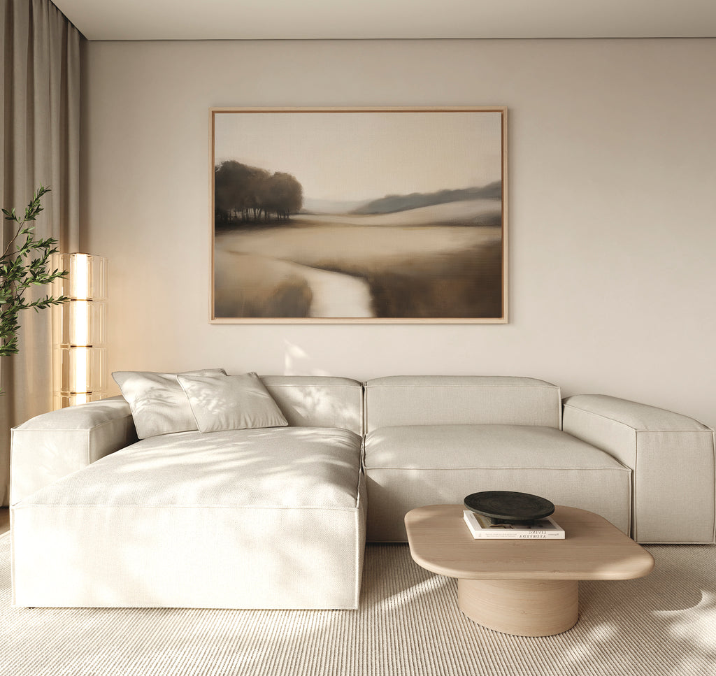 A minimalist living room with a light beige sectional sofa, wooden coffee table, Vintage Horizon Canvas Art – Horizontal on the wall, and a plant in the corner, all in soft neutral tones.