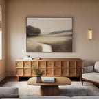 A cozy living room with beige walls features the Vintage Horizon Canvas Art – Horizontal above a wooden sideboard with circular patterns, a small coffee table, a vase of flowers, and a light gray sofa bathed in natural light.