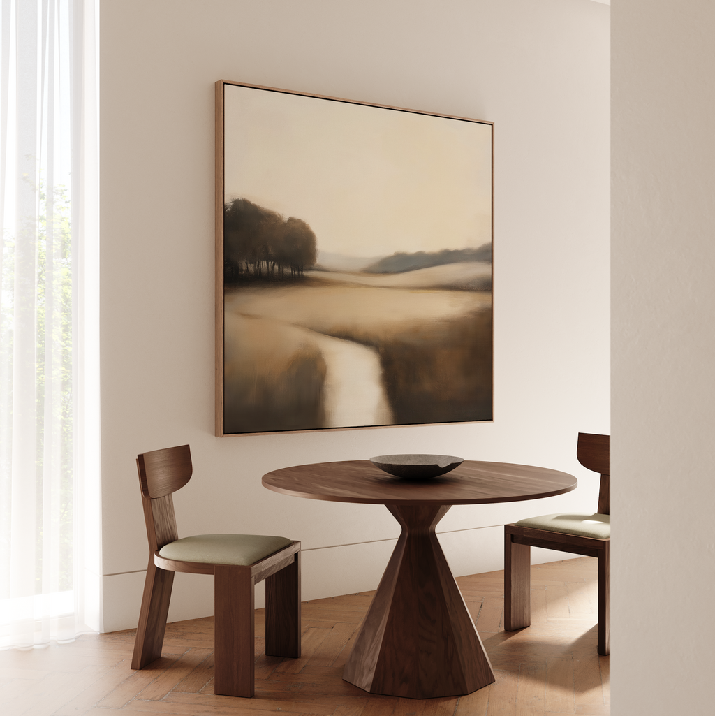A minimalist dining area features a round wooden table, two cushioned chairs, and Vintage Horizon Canvas Art above. Sunlight streams through sheer curtains, creating a calm space perfect for relaxing dining or living room decor inspiration.