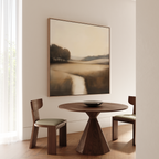 A minimalist dining area features a round wooden table, two cushioned chairs, and Vintage Horizon Canvas Art above. Sunlight streams through sheer curtains, creating a calm space perfect for relaxing dining or living room decor inspiration.