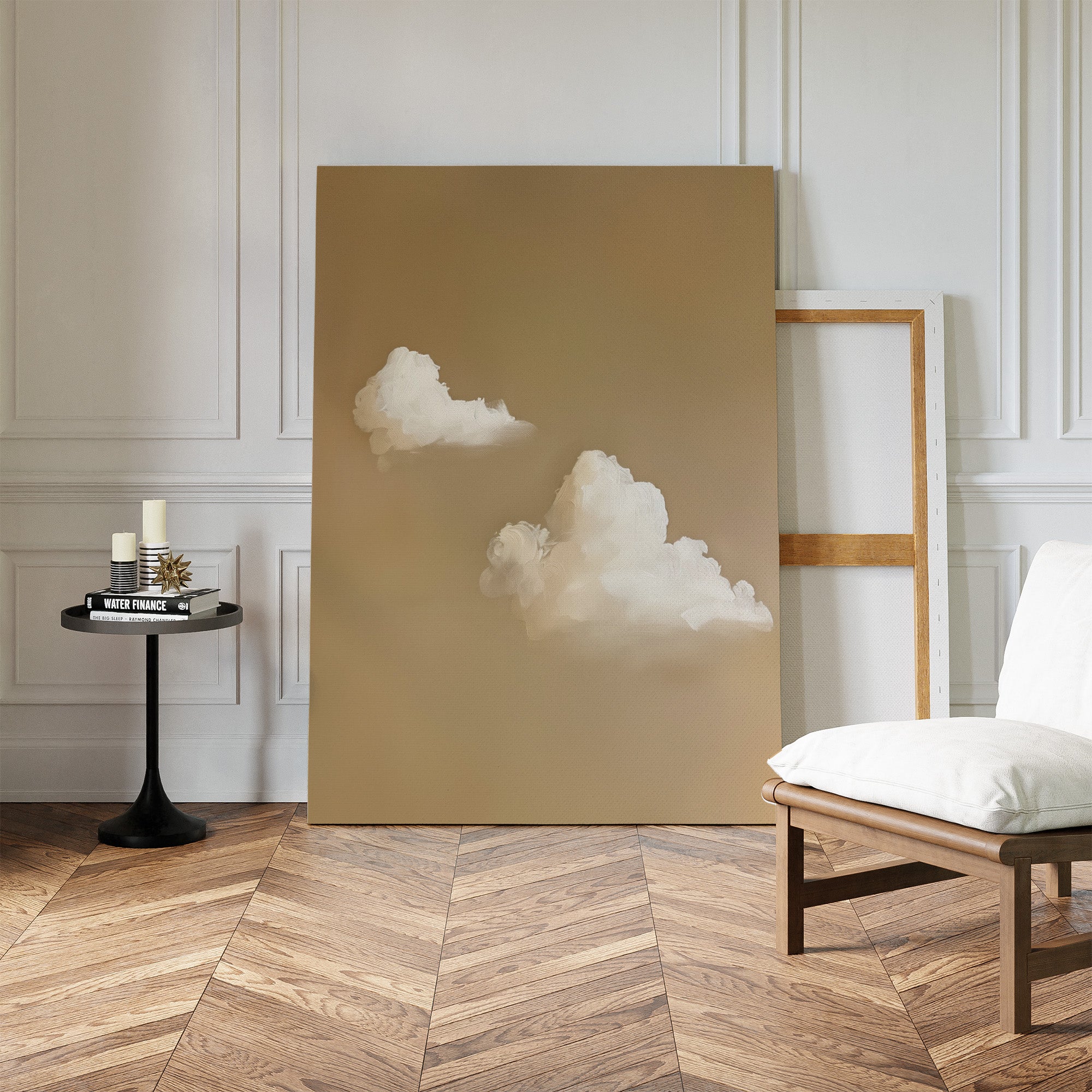 A minimalist room with a herringbone wood floor features “Whispering Clouds”—a large minimalist wall art piece with white clouds on beige—leaning against a white wall, complemented by a modern chair and black side table for chic decor.