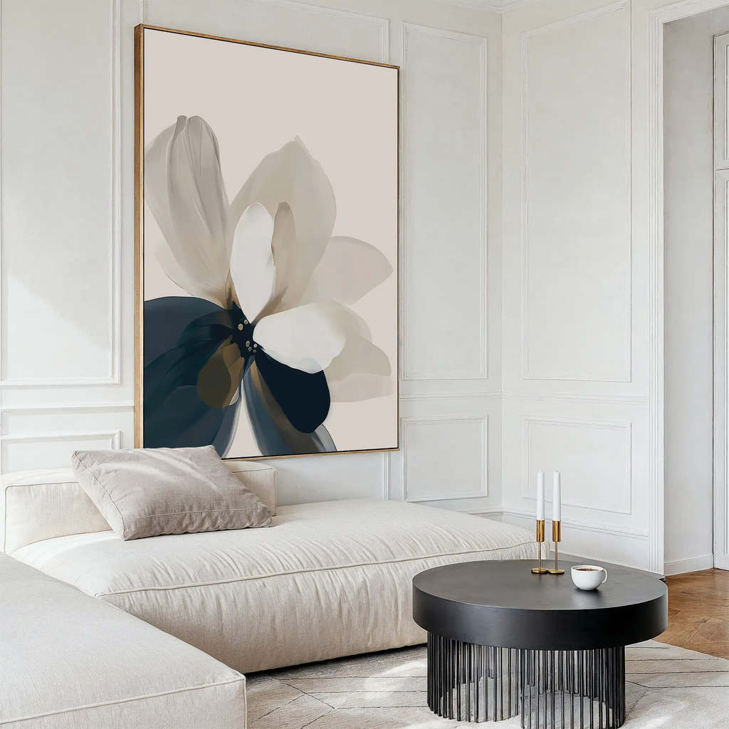 A modern living room with a light sectional sofa, beige pillow, round black coffee table, and Whispering Petals Canvas Art - Vertical. White paneled walls and minimal decor complete this tasteful neutral space.