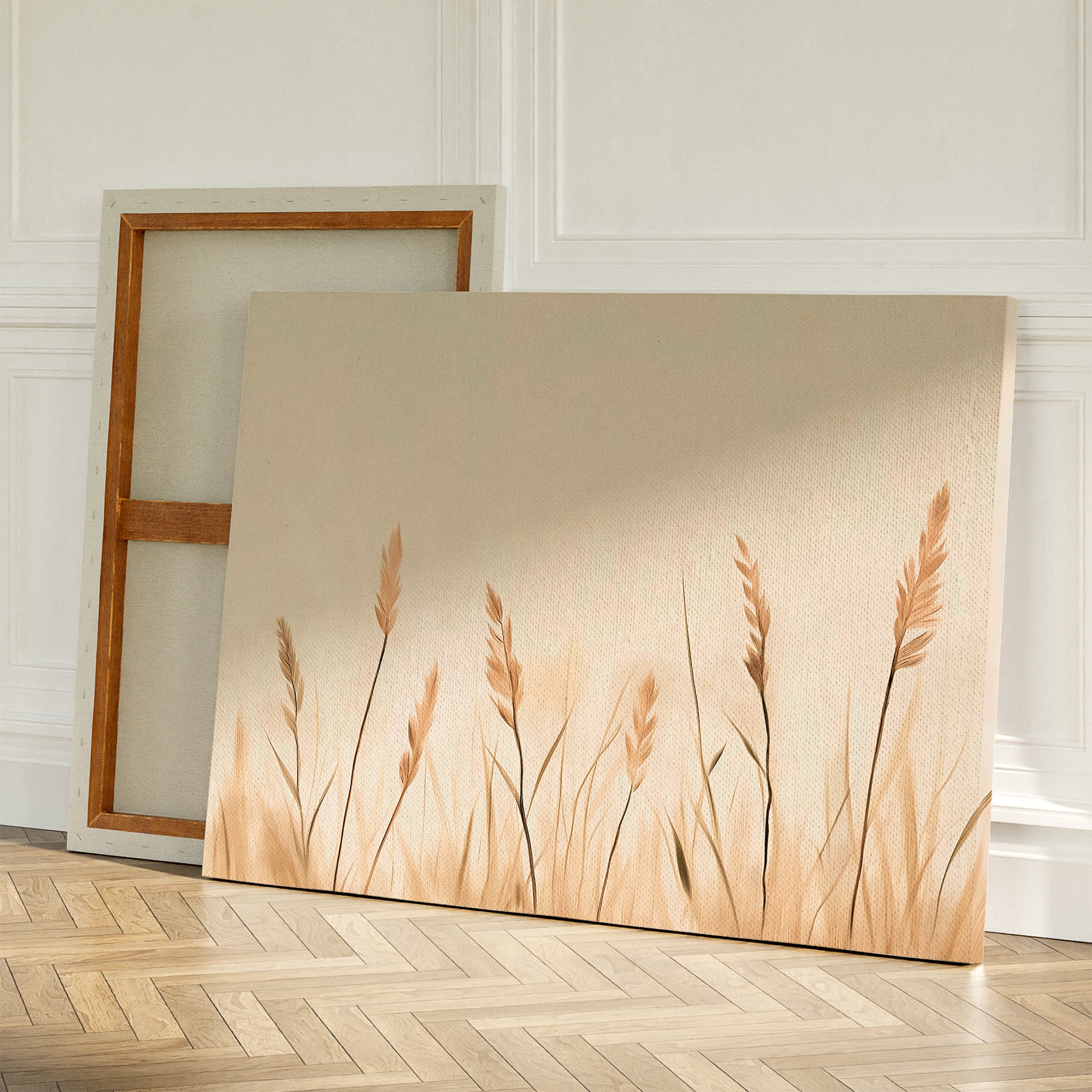 Two canvases rest on a wooden floor against a white wall; one is turned to show its frame while the other displays Whispering Reeds Canvas Art, featuring beige and brown wheat-like plants—ideal minimalist wall art for your living room decor.