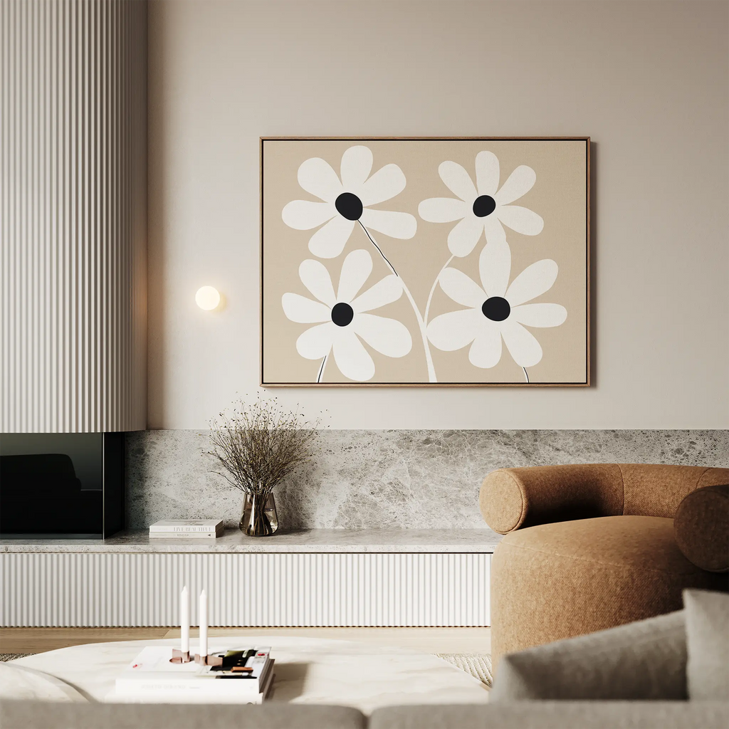 A modern living room in neutral tones features the White Blooms Canvas Art—an abstract daisy piece—paired with a beige curved sofa, marble-topped low shelf, dried flowers in a vase, and soft ambient lighting.