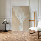 A minimalist living space with herringbone wood floors features the White Flame Abstract Canvas Art leaning against the wall, a black side table with candles, an empty frame, and a white cushioned chair.