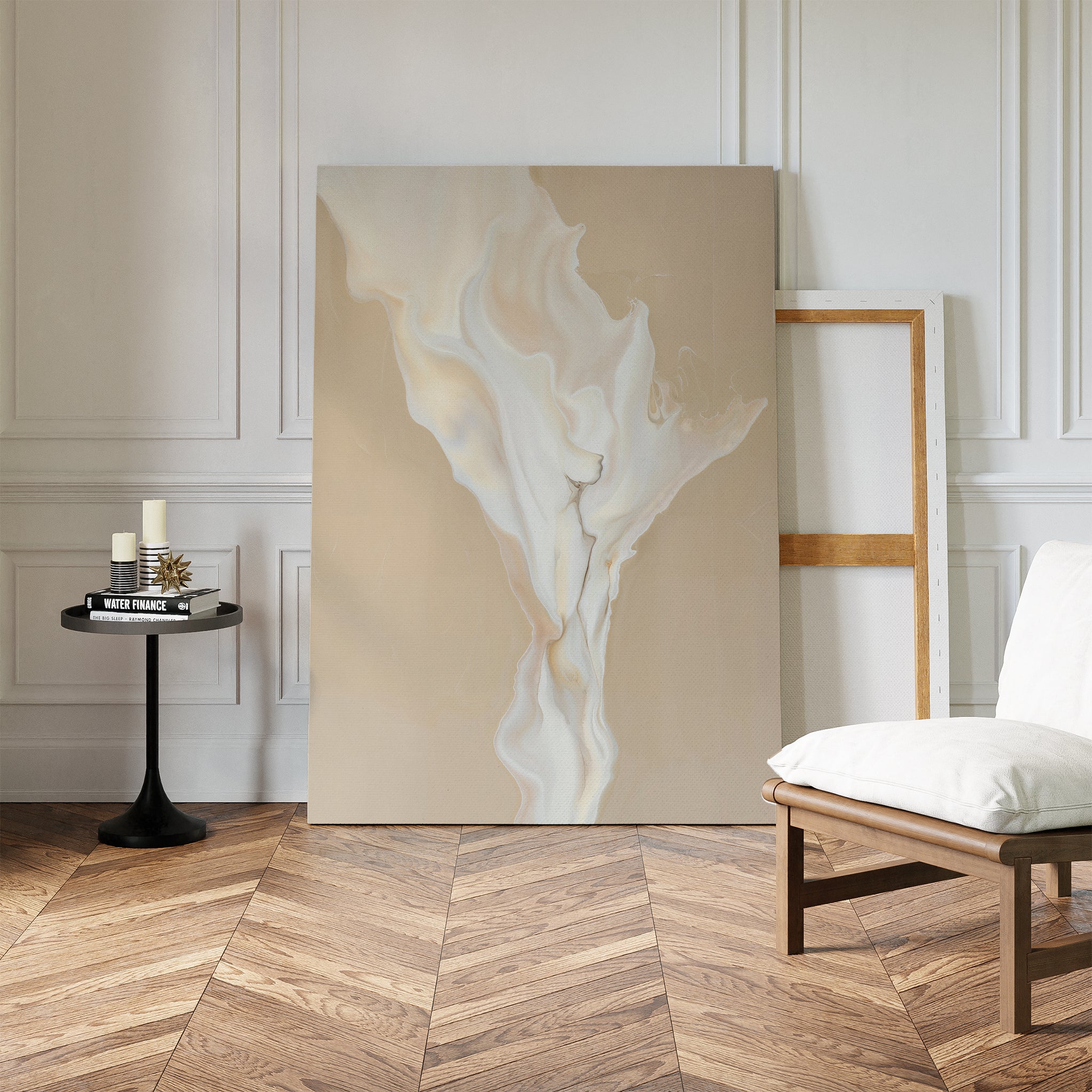 A minimalist living space with herringbone wood floors features the White Flame Abstract Canvas Art leaning against the wall, a black side table with candles, an empty frame, and a white cushioned chair.