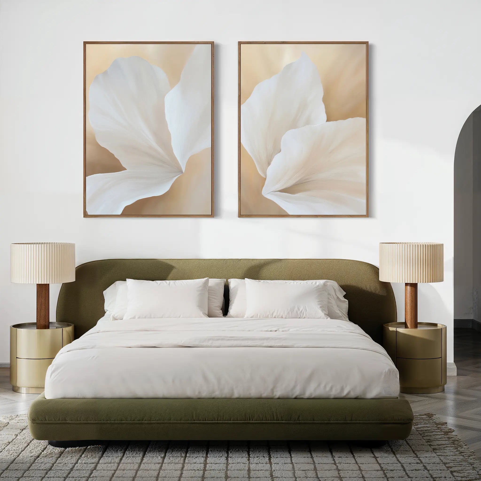 A modern bedroom with a green upholstered bed, white bedding, and two beige lamps on round nightstands. The White Flora Set of 2 botanical wall art hangs above the headboard, complementing the textured area rug.