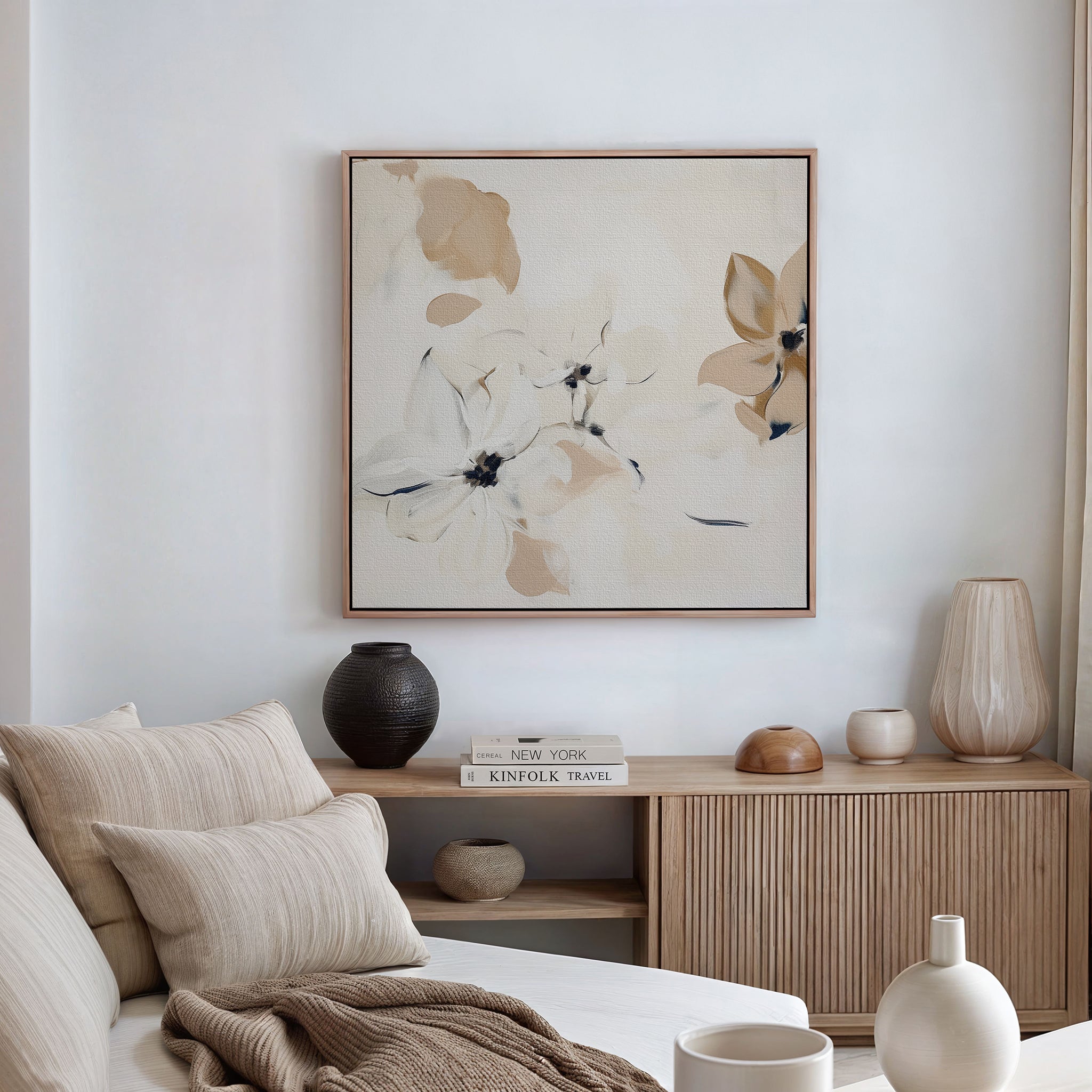 A cozy, neutral-toned living room with a beige sofa, soft pillows, wooden sideboard, vases, and minimalist wall art—a framed White Whispers Canvas Art in cream and tan tones—perfectly completes the decor.