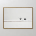 Winter Silence Canvas Art features a snow-covered landscape with two bare trees beneath a pale sky and birds gliding above, creating serene minimalist wall decor.