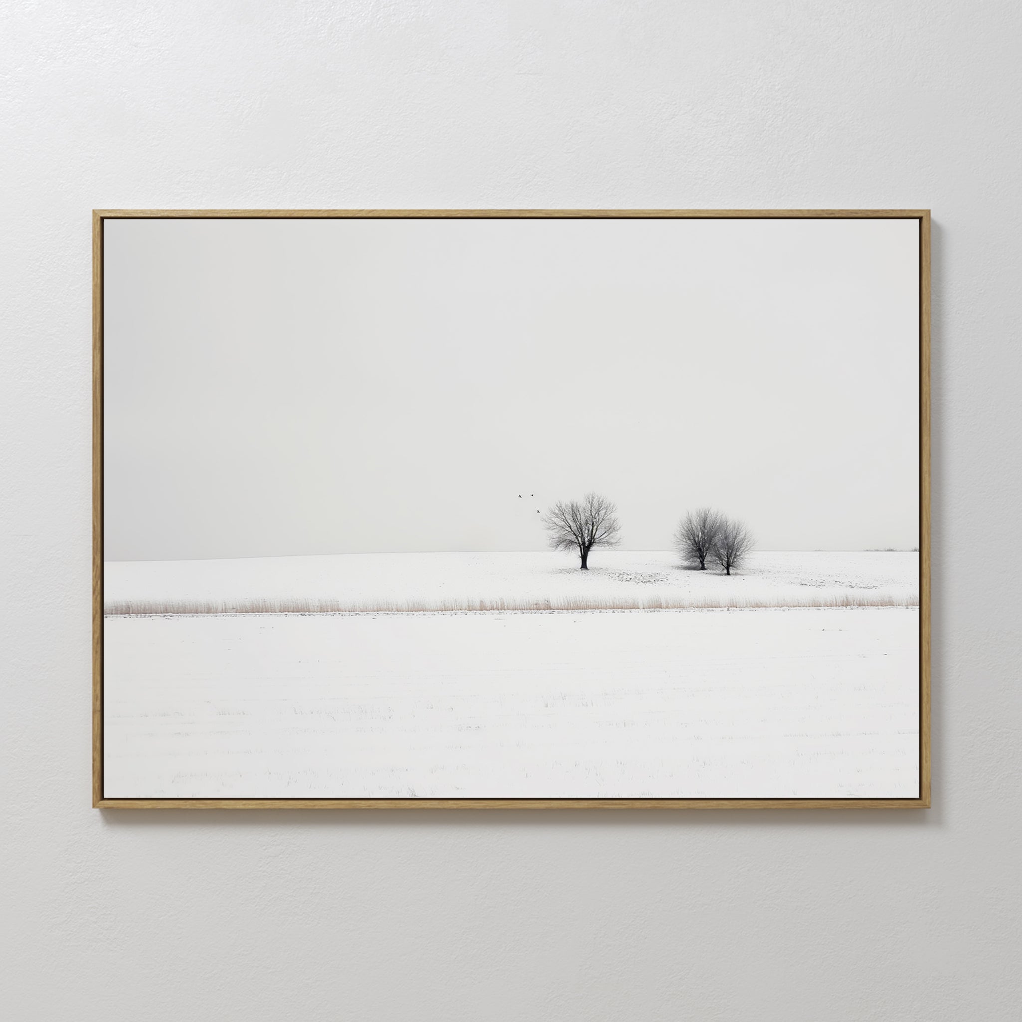Winter Silence Canvas Art features a snow-covered landscape with two bare trees beneath a pale sky and birds gliding above, creating serene minimalist wall decor.