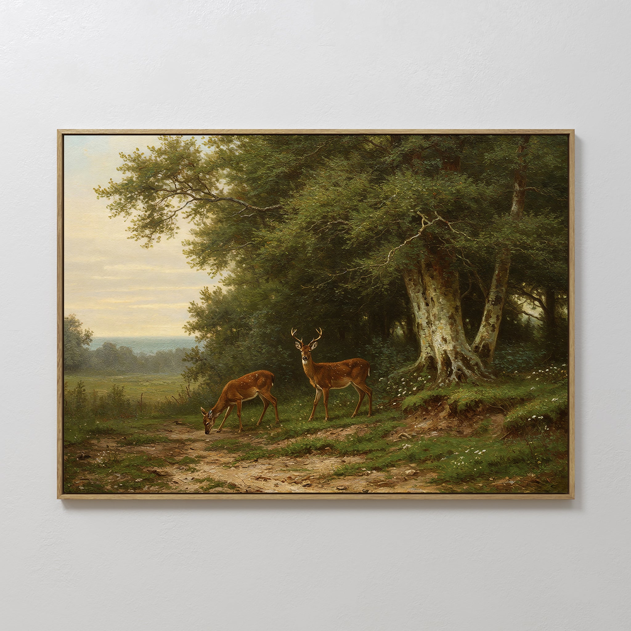 The Woodland Watch Canvas Art features two deer on a dirt path near a forest, surrounded by tall trees and fields under a cloudy sky. One grazes while the other stands alert—ideal wall decor for nature lovers. Framed and large size available.
