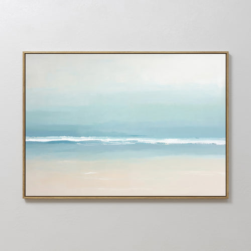 The Airy Shore Canvas Art - Horizontal captures a minimalist seascape in soft blue and white tones, with gentle waves, a sandy beach, and a pale sky evoking a calm coastal atmosphere.