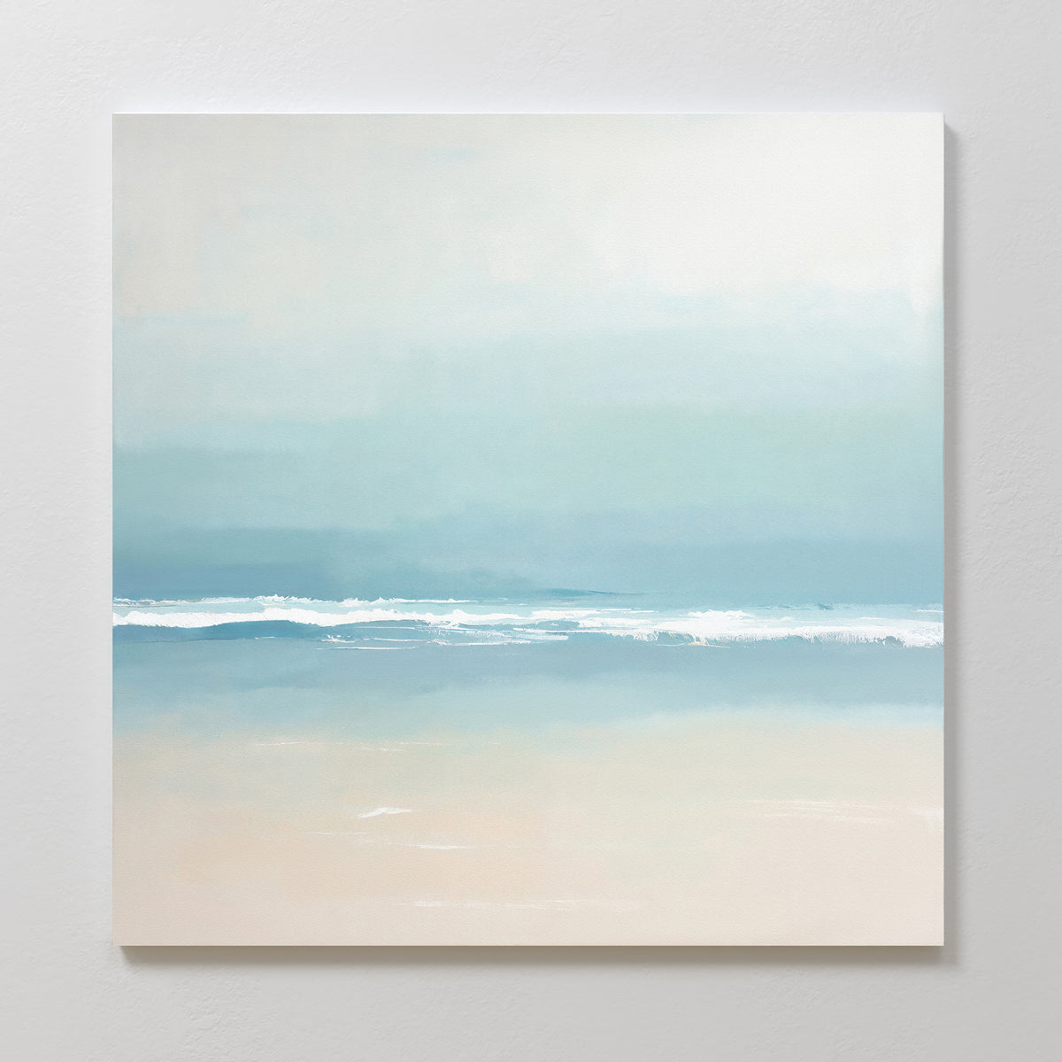 The Airy Shore Canvas Art - Square features a minimalist Nordic seascape in soft blue and beige tones, with gentle waves under a hazy sky, perfect for adding calm elegance to a light-colored wall.