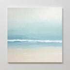 The Airy Shore Canvas Art - Square features a minimalist Nordic seascape in soft blue and beige tones, with gentle waves under a hazy sky, perfect for adding calm elegance to a light-colored wall.