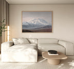 A modern living room features a light beige sectional sofa, a wooden coffee table, and the Alpine Majesty Canvas Art - Horizontal above the sofa. Soft natural light streams in through a window with sheer curtains.