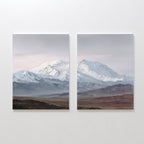 Alpine Majesty - Set of 2 showcases side-by-side mountain canvas prints with snow-capped peaks, a cloudy sky, and earthy plains. This Nordic Park-inspired wall art features serene, muted tones for a calming decor accent.