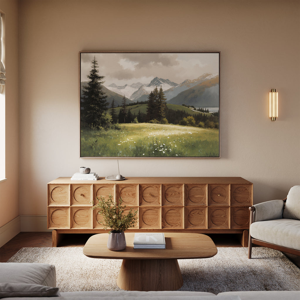 A cozy living room with a wooden sideboard, coffee table, and light sofa. Above the sideboard hangs the Alpine Meadow Canvas Art - Horizontal, while a vase with flowers decorates the table.
