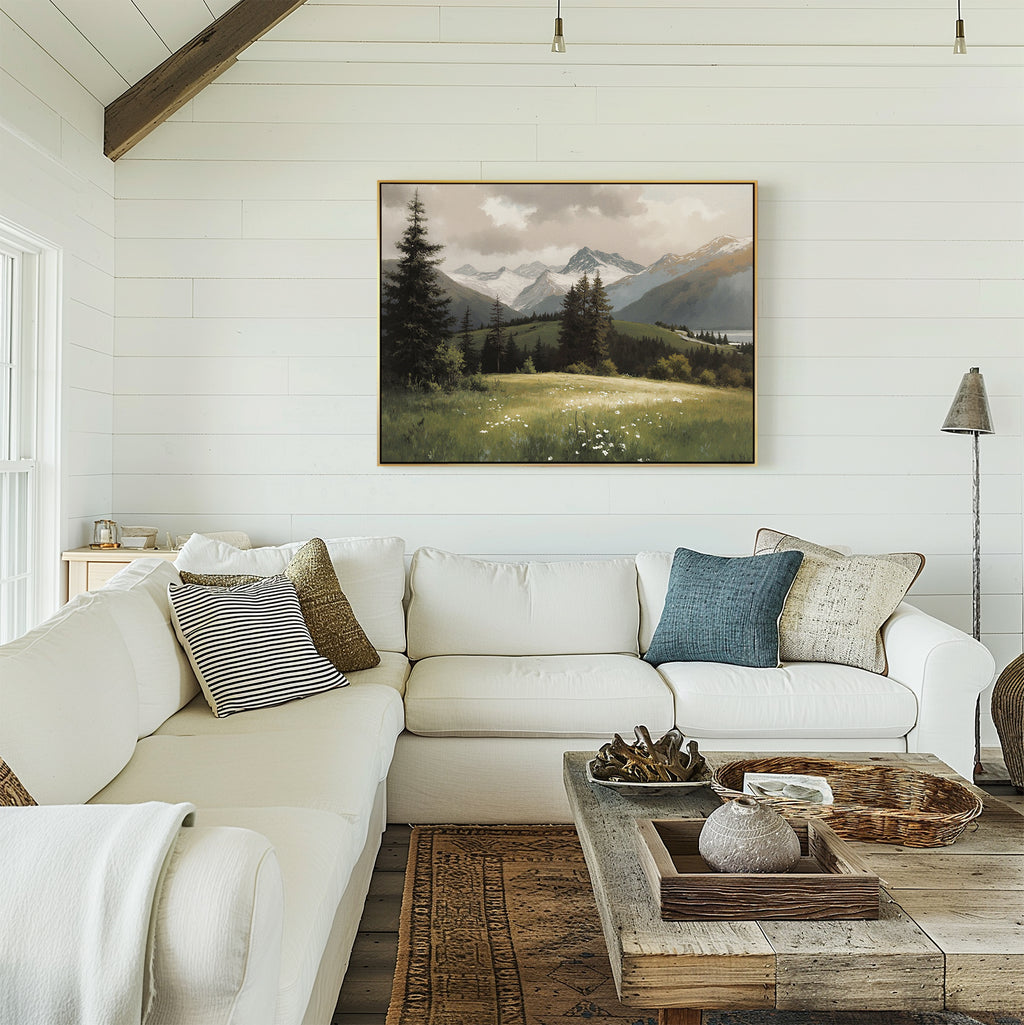 A bright, cozy living room features a white sectional sofa, assorted throw pillows, a rustic wooden coffee table, and the Alpine Meadow Canvas Art - Horizontal on a white shiplap wall. Natural light fills the space.