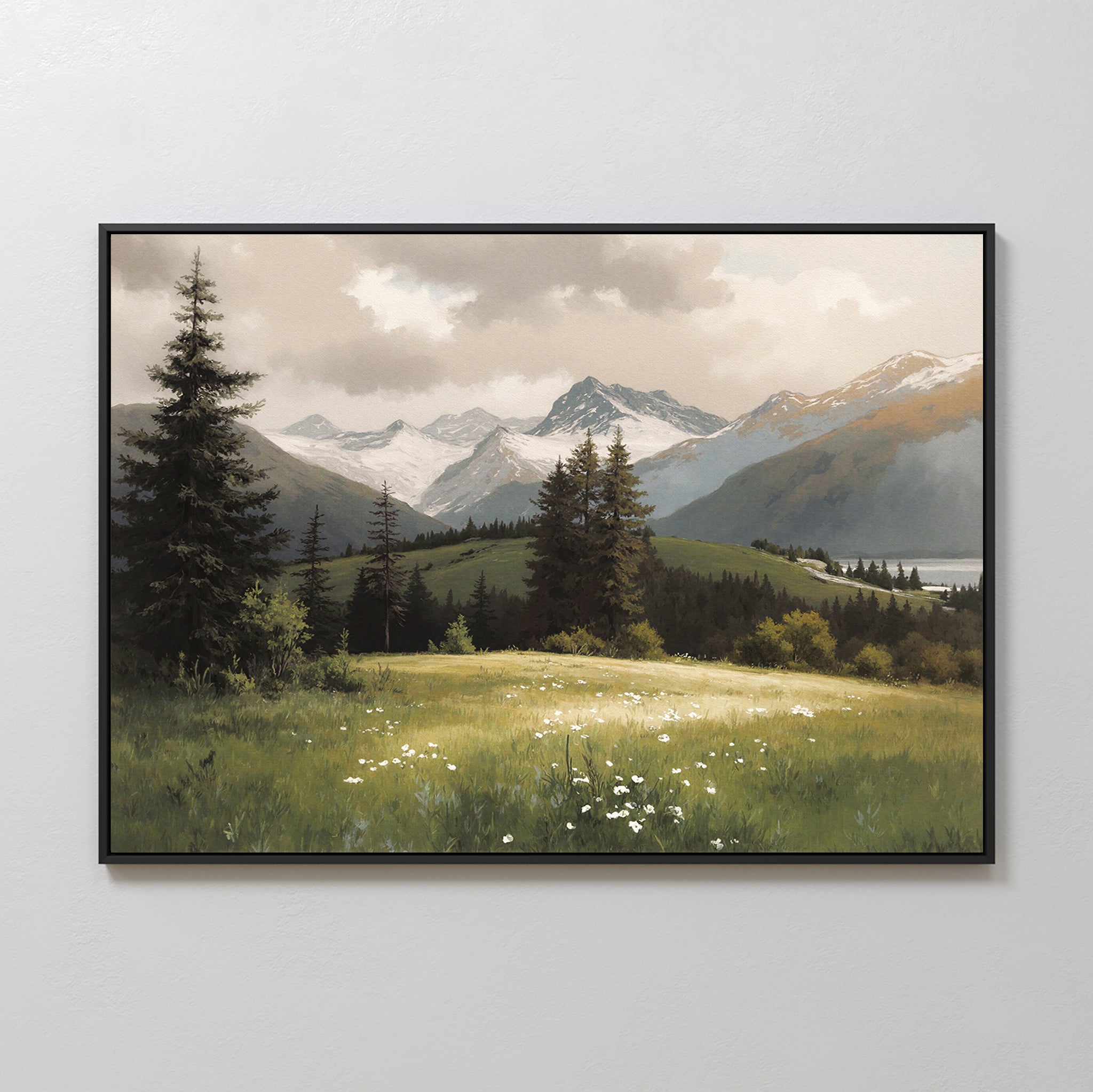 The Alpine Meadow Canvas Art - Horizontal features grassy hills, white wildflowers, tall evergreens, and distant snow-capped mountains under a cloudy sky, displayed on a plain light-colored wall.
