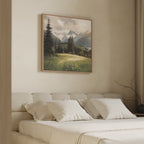 A neatly made bed with white pillows and blankets sits beneath the Alpine Meadow Canvas Art - Square, which showcases a mountain landscape with trees and grassy fields. The room has light walls and simple, elegant decor.