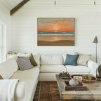 A cozy living room with white shiplap walls, a white sectional sofa with assorted pillows, a rustic wooden coffee table, and the Amber Horizon Canvas Art - Horizontal hanging above the couch.