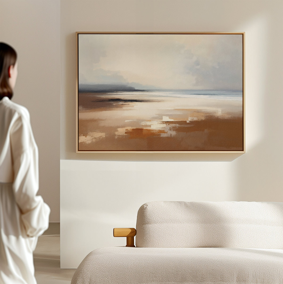 A person stands in a minimalist, neutral-toned room, gazing at the Amber Shore Canvas Art - Horizontal displayed above a light-colored sofa.