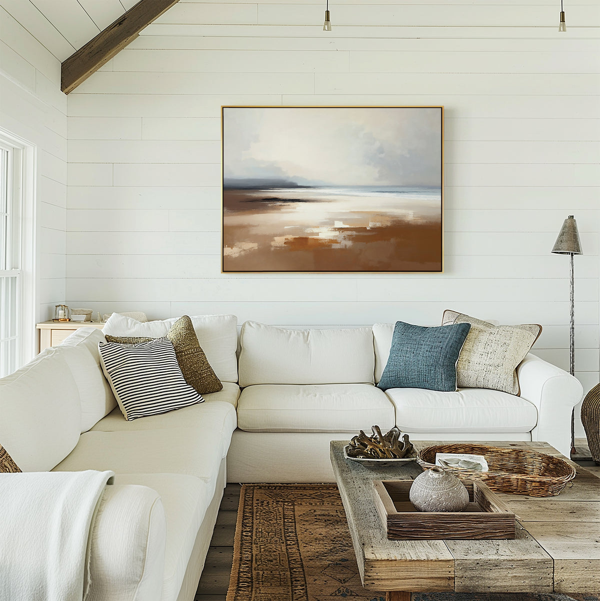 A bright, cozy living room features a white sectional sofa, neutral throw pillows, a rustic wooden coffee table, and the Amber Shore Canvas Art - Horizontal displayed on a white shiplap wall. Natural light streams in from the left.