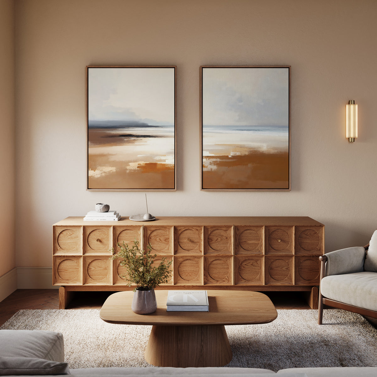 A cozy living room with a wooden sideboard, "Amber Shore - Set Of 2" modern abstract wall art, a wooden coffee table with a vase and book, beige armchair, and soft lighting creating a warm, inviting atmosphere.