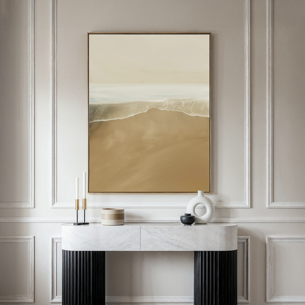 A minimalistic room features a marble console table, decorative objects, and the Sand and Sea Abstract Canvas Art—framed and depicting a serene shoreline—hanging on a light-paneled wall for neutral home decor.