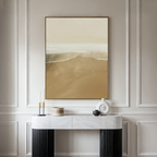 A minimalistic room features a marble console table, decorative objects, and the Sand and Sea Abstract Canvas Art—framed and depicting a serene shoreline—hanging on a light-paneled wall for neutral home decor.