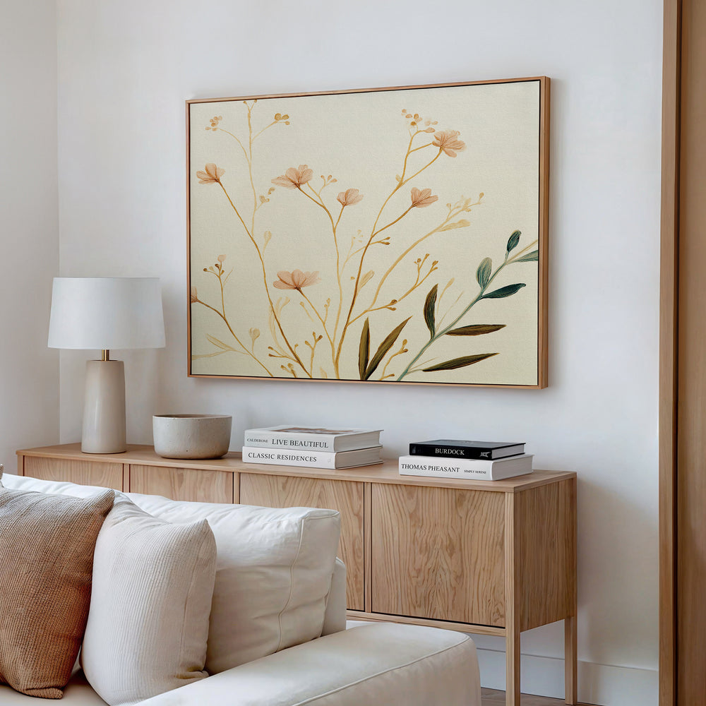 A modern living space with a light wood sideboard, neutral decor—stacked books, ceramic bowl, white lamp—and the Autumn Botanicals Canvas Art - Horizontal hanging above, featuring delicate flowers and leaves.