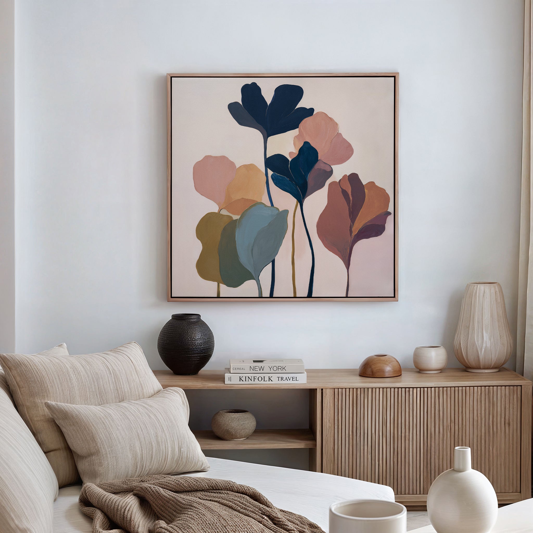 A cozy living room with a beige sofa, striped cushions, and ceramic vases features the Autumn Garden Canvas Art - Square—a framed abstract painting of colorful leaves—enhancing the calm, minimalist atmosphere with modern decor.