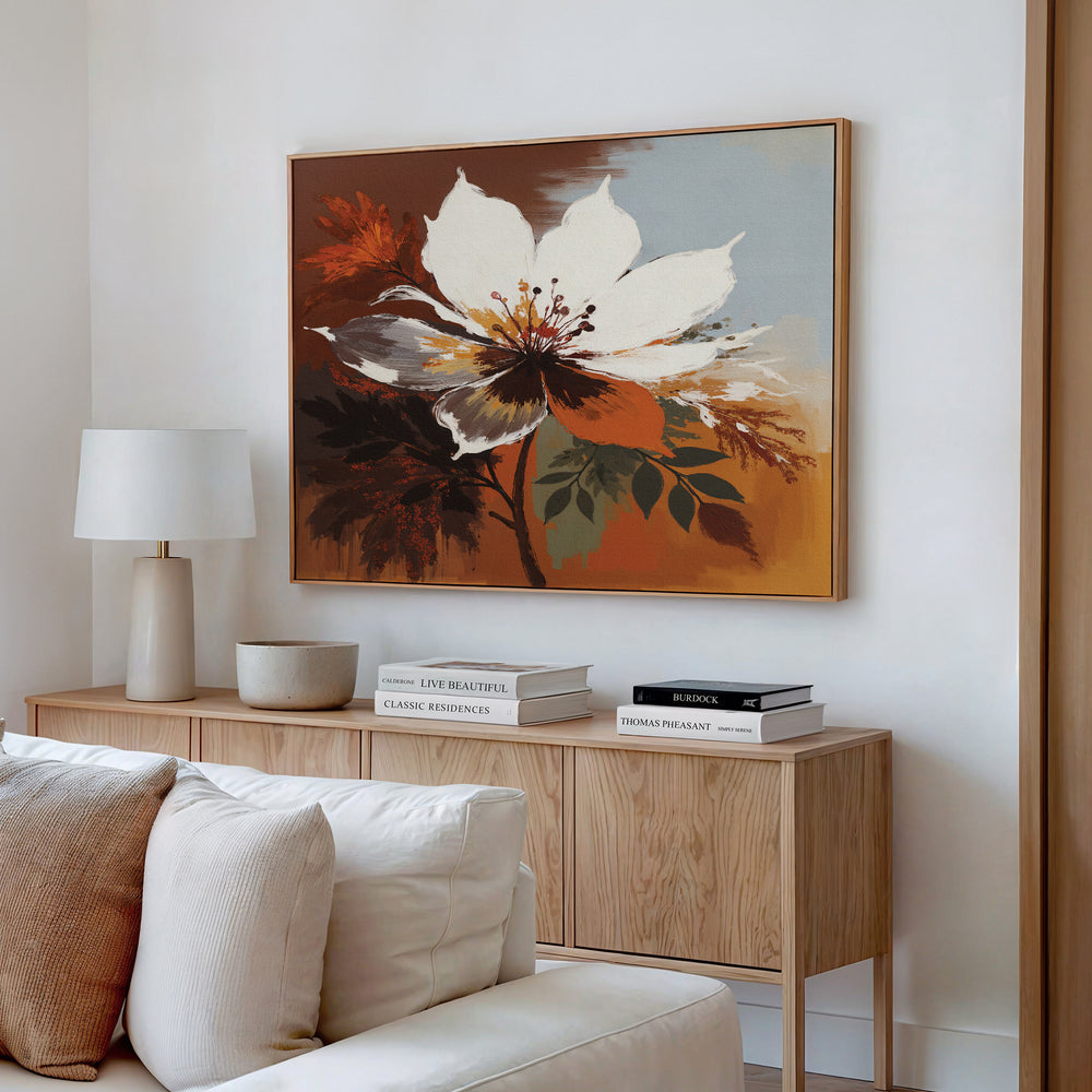 A modern living room features a wooden sideboard with stacked books, a lamp, and a ceramic bowl. Above it hangs the Autumn Radiance Canvas Art - Horizontal, while a cream sofa with cushions sits in the foreground.