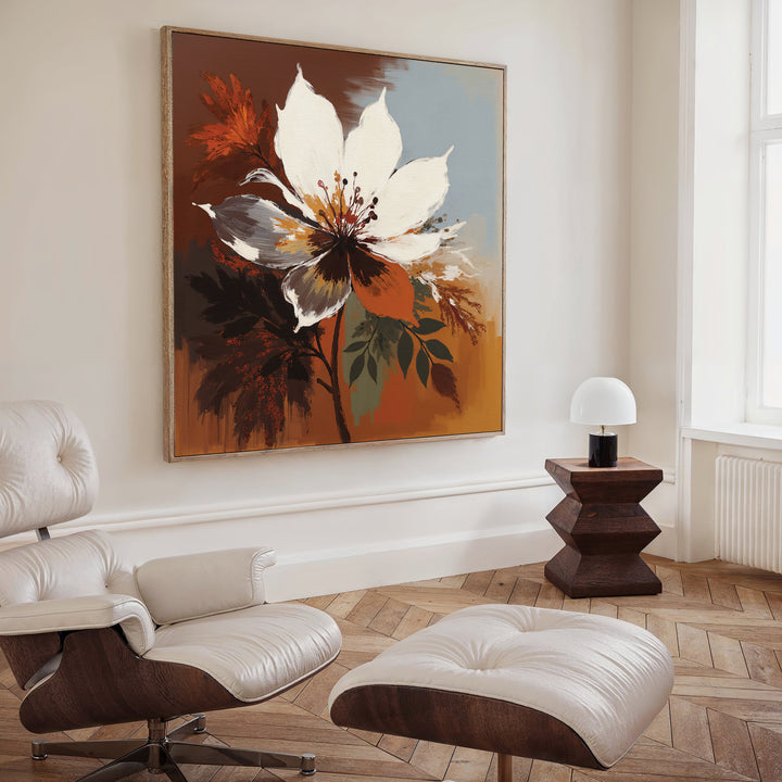 A modern living room features a white leather lounge chair and ottoman, a dark wood side table with a small white lamp, and the Autumn Radiance Canvas Art - Square as a bold statement on the wall. Light pours in through a tall window.