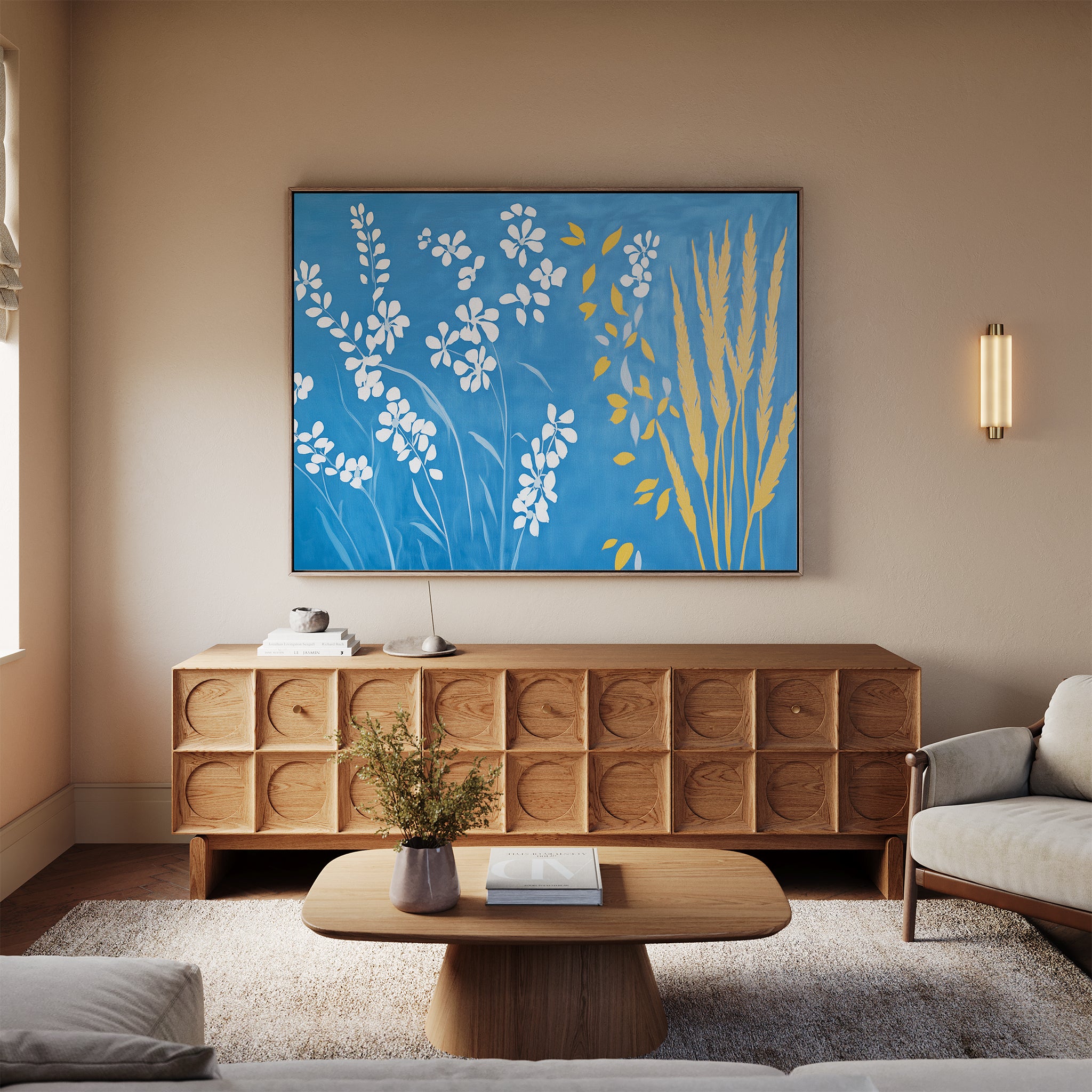 A modern living room with a light sofa, wooden coffee table topped with a vase of flowers, and sideboard. The Azure Meadow Canvas Art - Horizontal, in blue, white, and yellow botanicals, hangs above the sideboard.