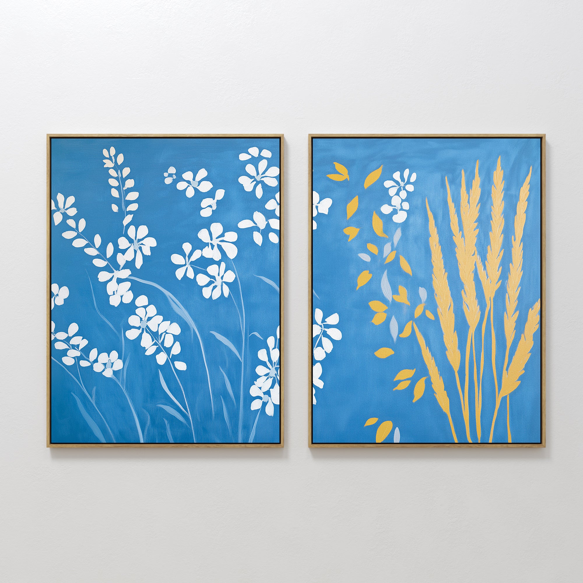 The Azure Meadow - Set of 2 adds charm to the wall: one print features white wildflowers on blue, while the other displays yellow wheat stalks and leaves on an azure background.