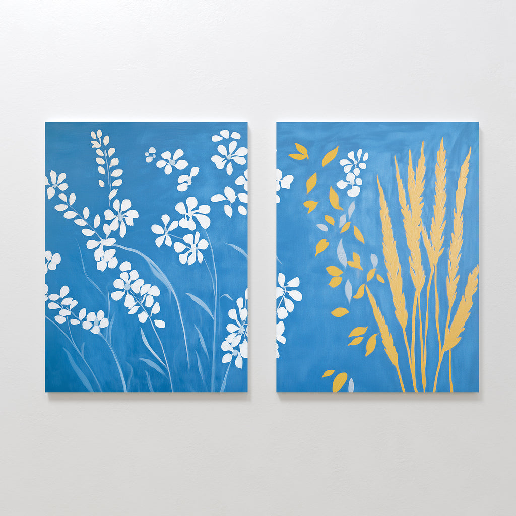 The Azure Meadow - Set of 2 features blue canvases: the left shows white wildflower silhouettes, while the right displays yellow wheat and leaf shapes with some white flowers on the left—bringing serene meadow vibes to your space.