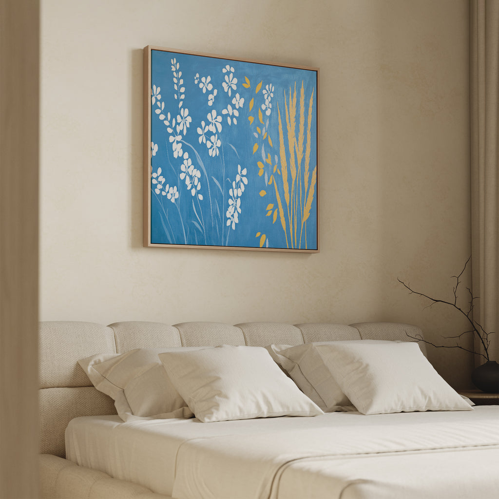 A modern bedroom with a beige upholstered bed, white bedding, and the Azure Meadow Canvas Art - Square featuring blue, white, and yellow botanical designs above the headboard. Neutral walls and curtains complete the calming look.