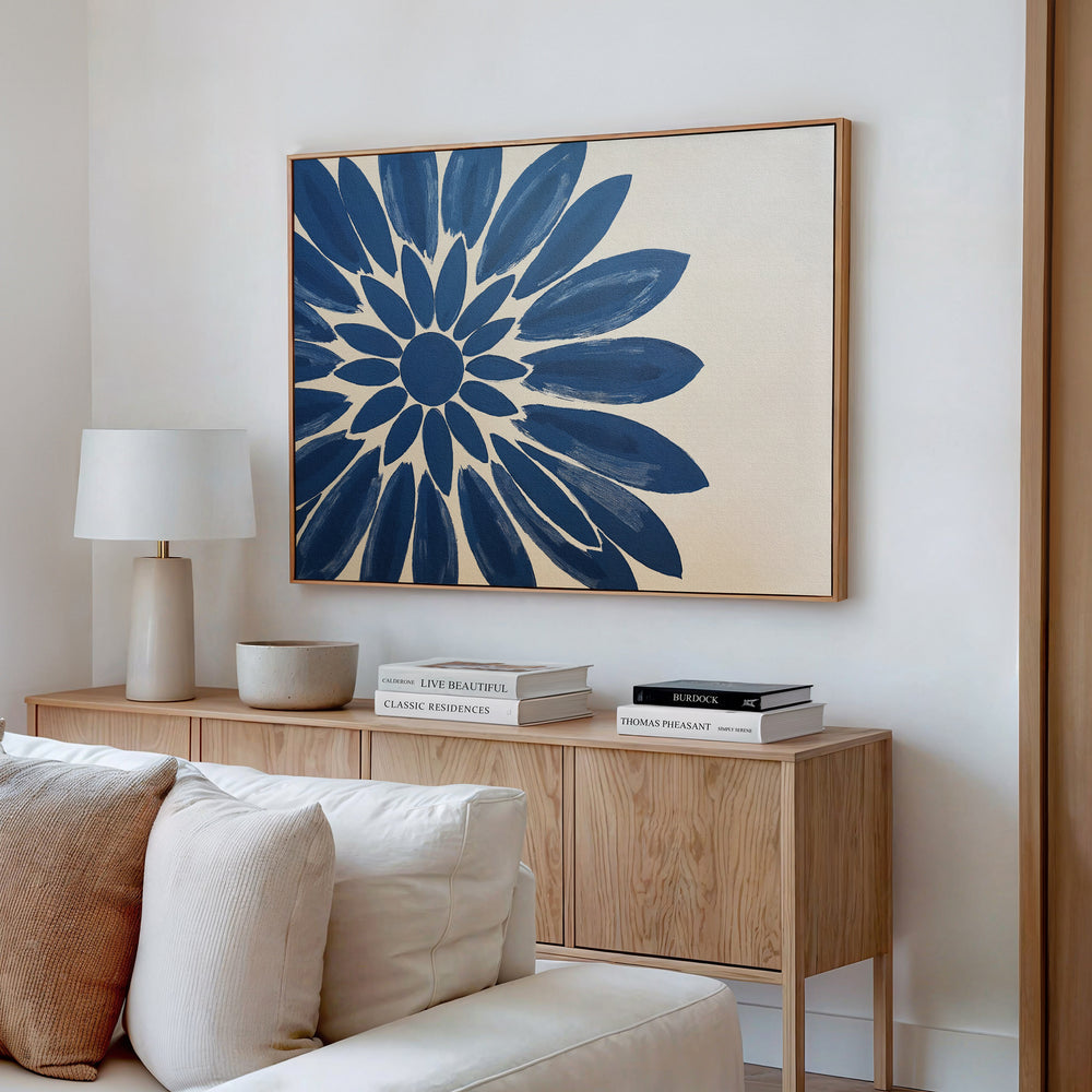 A modern living room featuring a wooden sideboard, lamp, decorative bowl, stacked books, and the Azure Radiance Canvas Art - Horizontal in blue floral tones above a beige sofa—ideal for those who love modern living room decor.