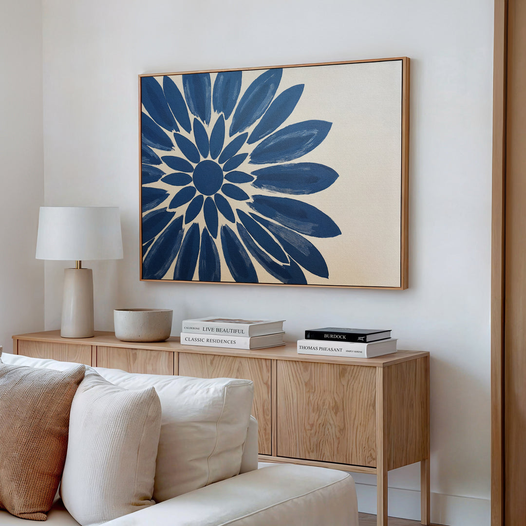 A modern living room featuring a wooden sideboard, lamp, decorative bowl, stacked books, and the Azure Radiance Canvas Art - Horizontal in blue floral tones above a beige sofa—ideal for those who love modern living room decor.