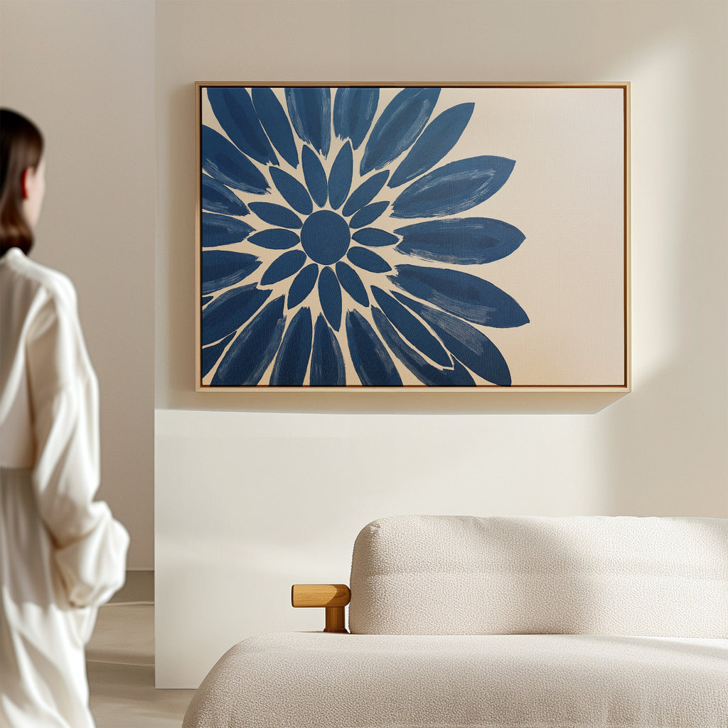 A person stands in a minimalistic room, admiring the Azure Radiance Canvas Art - Horizontal featuring a bold blue flower. A light sofa beneath the artwork creates a striking focal point for modern living room decor.
