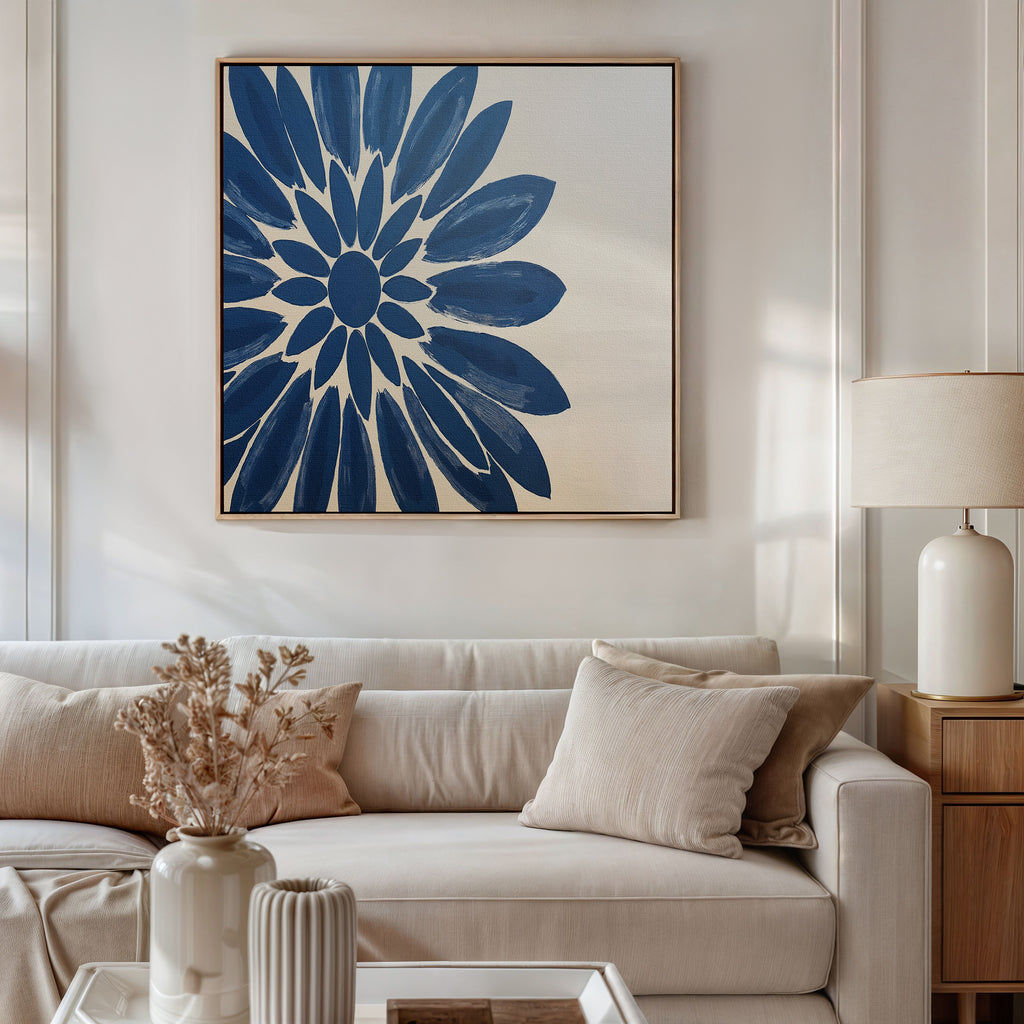 A modern living room with a beige sofa, neutral cushions, a white table lamp, and the Azure Radiance Canvas Art - Square featuring a bold blue flower. Dried flowers in a white vase on the coffee table complete this stylish modern decor.