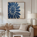 A modern living room with a beige sofa, neutral cushions, a white table lamp, and the Azure Radiance Canvas Art - Square featuring a bold blue flower. Dried flowers in a white vase on the coffee table complete this stylish modern decor.