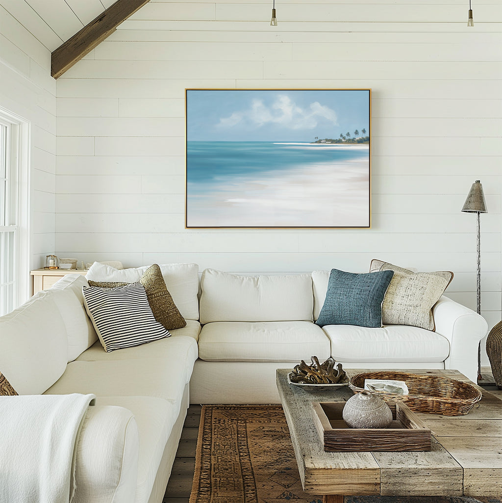 Bright, airy living room with white shiplap walls, a large white sectional sofa adorned with assorted pillows, a rustic wooden coffee table, and the Azure Tranquility Canvas Art - Horizontal of turquoise waters displayed above the sofa.