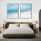 A modern bedroom with a green upholstered bed, white bedding, two beige nightstands with lamps, and serene wall art—Azure Tranquility - Set of 2—featuring large beach-themed paintings above the bed.