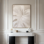 A modern console table with decorative objects stands beneath the Leaf Whisper Abstract Canvas Art, which showcases a neutral-toned monstera leaf against elegant, light-colored paneled walls.
