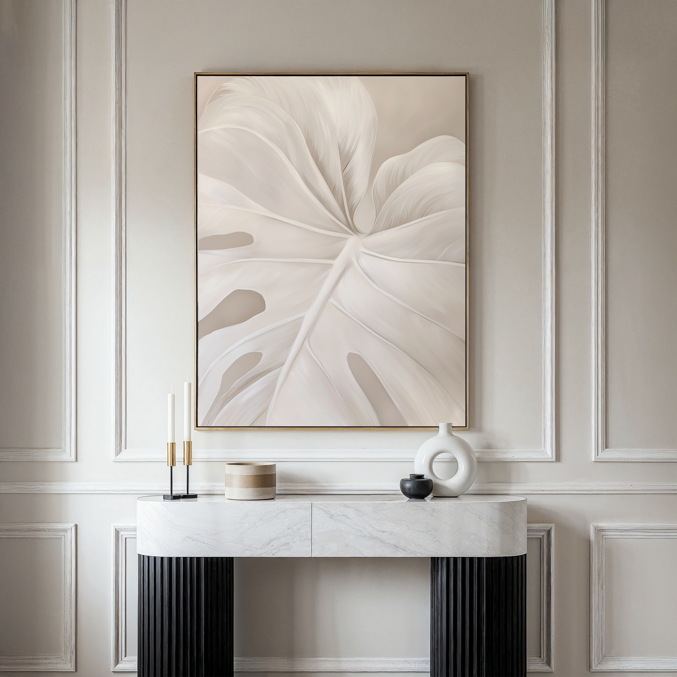 A modern console table with decorative objects stands beneath the Leaf Whisper Abstract Canvas Art, which showcases a neutral-toned monstera leaf against elegant, light-colored paneled walls.
