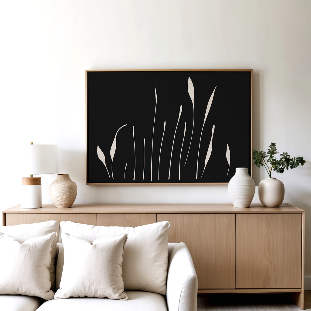 A modern living room features a light wood sideboard, white vases, a table lamp, and the Botanical Silhouettes Abstract Canvas Art above a beige sofa with white cushions.